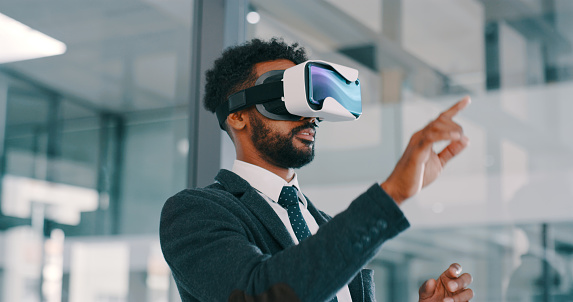 Shot of a young businessman using a virtual reality headset in a modern office