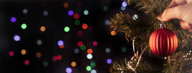 istock Christmas background concept- beautiful decor bauble hanging on the Christmas tree with sparkling light spot, blurry dark black background. 1252398938