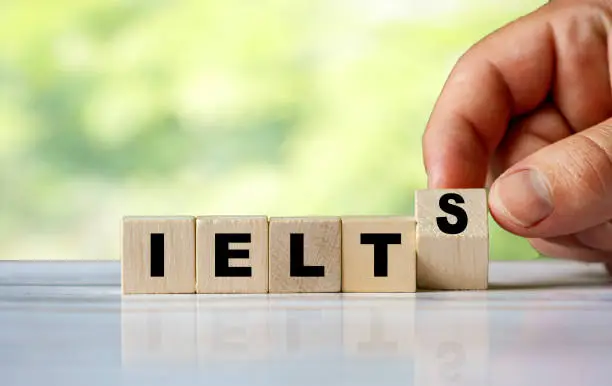 The hand turns the wooden cube and word IELTS