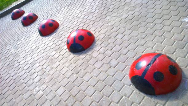 St. Petersburg, Russia - May 29, 2020: Five concrete hemispheres like red ladybugs to restrict movement and parking car. Speed ​​bumps on a footpath. Road safety regulations. Traffic rules. Safety in the city and residential district.