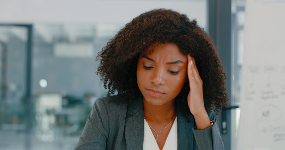 Shot of a young businesswoman looking stressed in a modern office