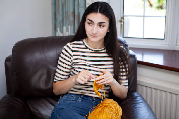 istock Young woman crocheting with yellow wool and looking up 1252402304
