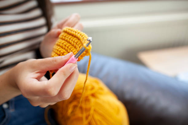 Young woman crocheting with yellow wool Close-up of hands doing crochet crochet photos stock pictures, royalty-free photos & images