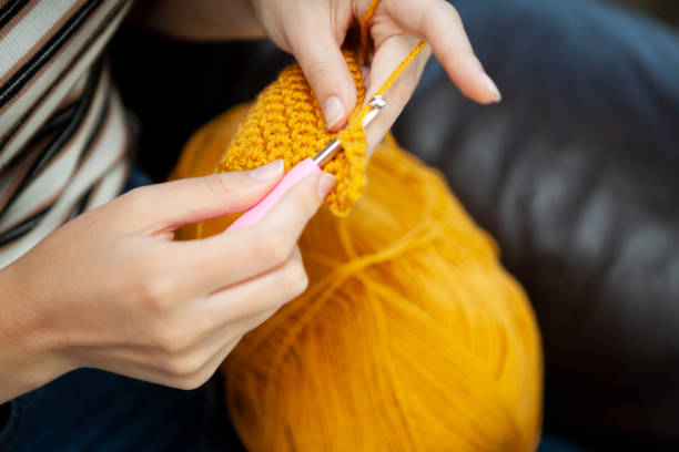 Close-up of hands doing crochet Close-up of hands doing crochet with yellow wool viewed from a high angle view crochet photos stock pictures, royalty-free photos & images
