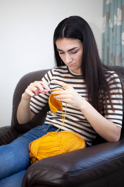 istock Young woman crocheting with yellow wool 1252403610