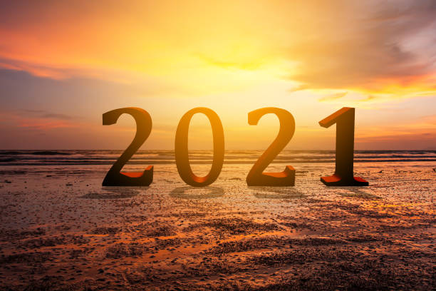 istock 2021 text on sand beach over blurred sunset sky background for new year concept. 1252404325