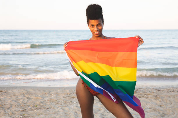 Woman holding a rainbow flag free on the beach