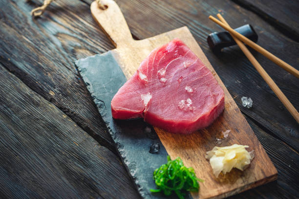 rohes thunfischsteak mit zutaten auf einem schneidebrett - vitamin d salmon fillet raw stock-fotos und bilder