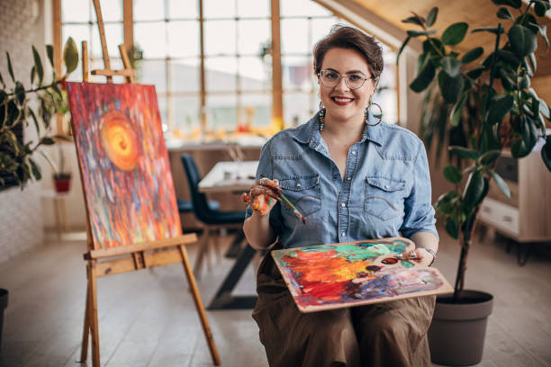 istock Young cheerful female artist working in her studio 1252407238