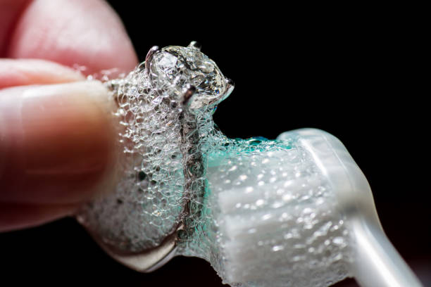 mãos da mulher limpando anel de diamante com escova de dentes e sabão - serviço de prata - fotografias e filmes do acervo