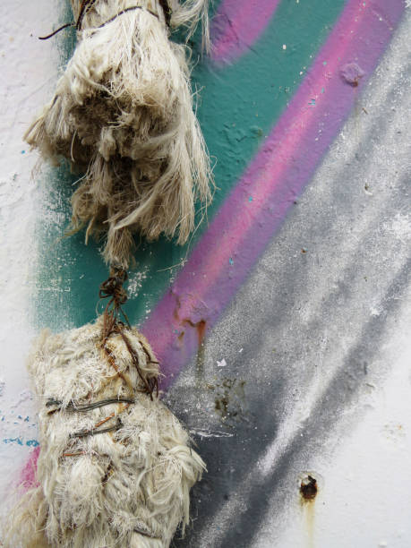 corde cassée, vieille et effilochée sur le mur rouillé avec des bandes de vert, gris et lilas. photographie macro originale du détail de corde cassée. arrière-plan et motif. - rope frayed breaking tied knot photos et images de collection