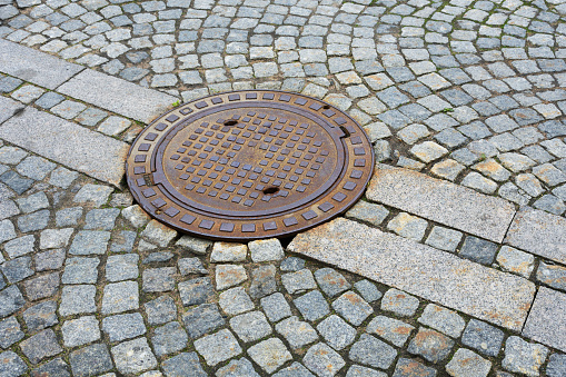 Sewer manhole on a city road.This is a heavy iron cover.