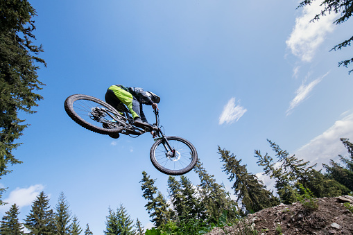 Attractive view of mountain biker flying in the sky, downhill riding in the mountain trail.