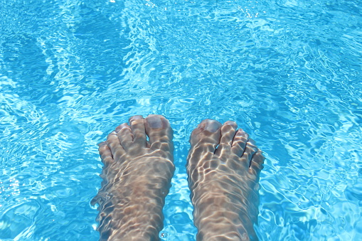 A woman's feet under water in a beautiful clear water pool creating ripples in Egypt