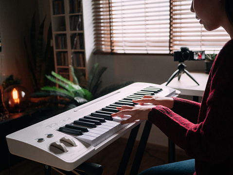 Home Alone Keyboard Piano Hobby Young woman Practicing Piano With Smartphone