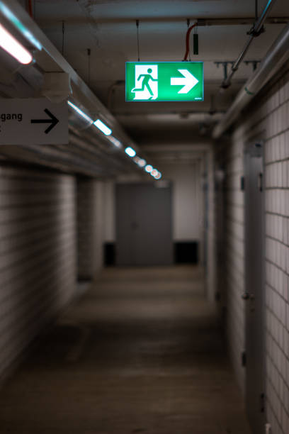 istock Illuminated green exit sign hanging from the wall in and underground poorly lit corridor 1252415184