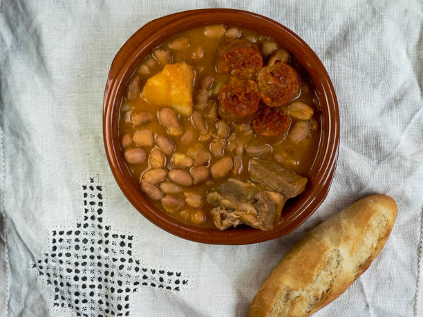 istock Asturian fabada, typical Spanish in a clay plate on wooden table with white tablecloth, top view 1252415225
