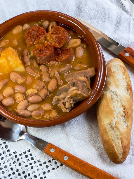 istock Asturian fabada, typical Spanish in a clay plate on wooden table with white tablecloth, top view 1252415227