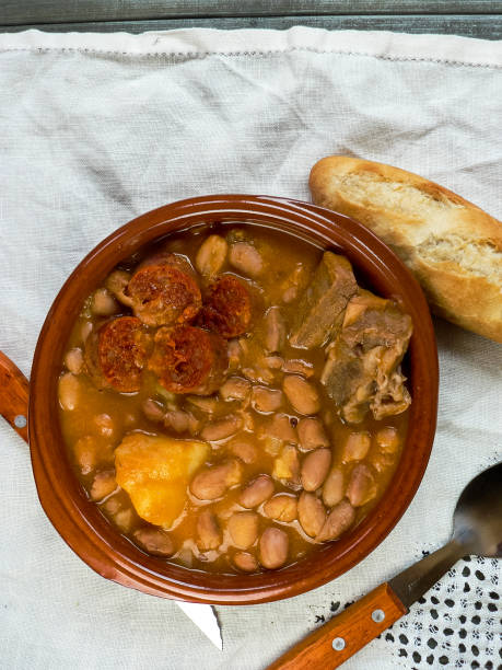 istock Asturian fabada, typical Spanish in a clay plate on wooden table with white tablecloth, top view 1252415229