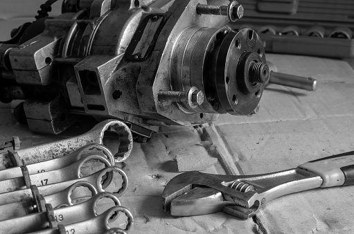High pressure fuel pump on a work bench next to wrenches. Detection of diesel fuel automotive equipment. Car service, auto repair. Black and white photo