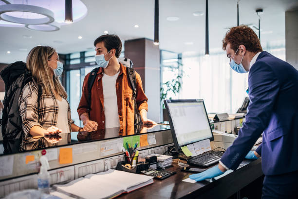 istock Young couple wearing protective face mask while doing check-in at the hotel reception 1252416631