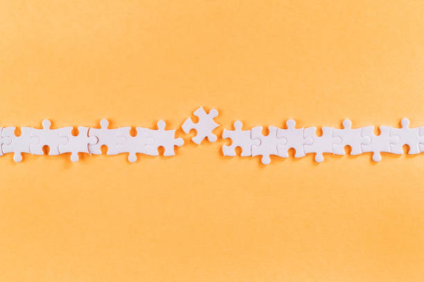 istock Disrupted row of white jigsaw puzzle pieces with missing link 1252416739