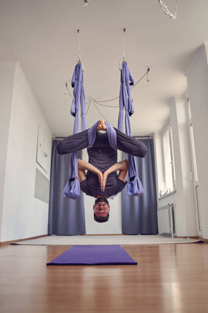 istock Athletic man doing inverted pigeon pose while practicing aerial yoga 1252417339