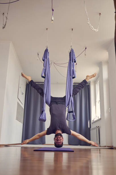 istock Bearded young man hanging upside down in yoga studio 1252417358