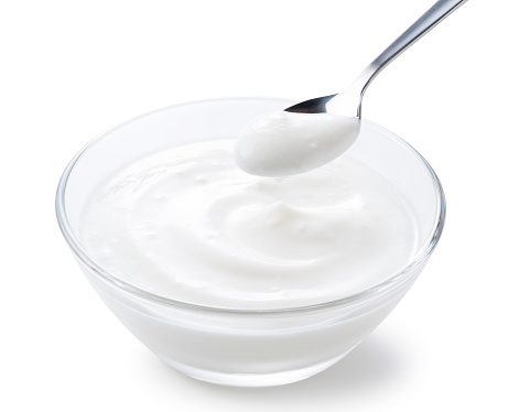 Yogurt in a glass bowl and a spoonful of yogurt.