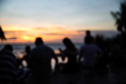 Beach Party at sunset with friends closed to swimming pool with ocean view. Blurred background.