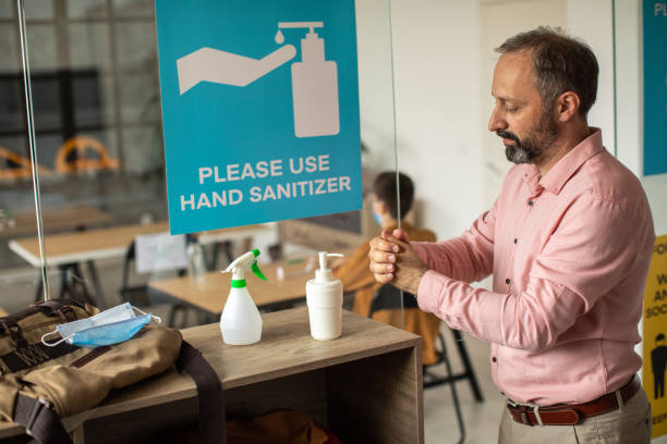 istock Teacher disinfecting hands with hand sanitizer before entering classroom 1252420210