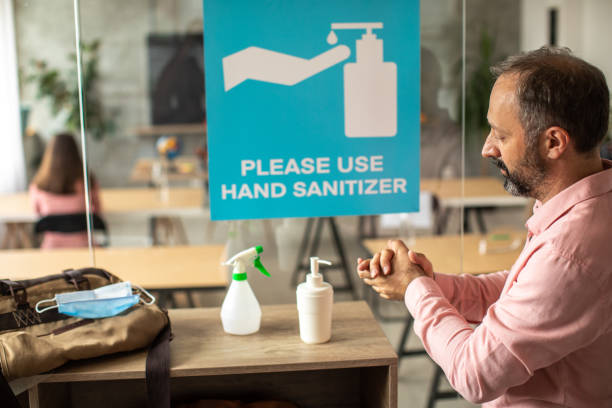 istock Teacher disinfecting hands with hand sanitizer before entering classroom 1252420589