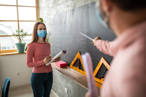 istock Teacher and student in front of blackboard at classroom 1252420646