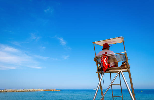 Barcelona, Spain - June 11, 2014: one lifeguard on the watching tower check the people who swim in the sea, Barceloneta beach, Barcelona, Catalonia, Spain, Europe. Barcelona beachfront, considered between 10 best urban beaches of the world.