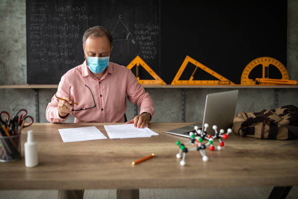 istock Teacher with protective face mask checking test results at classroom 1252421759