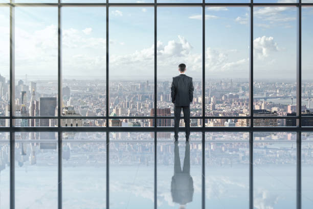 istock Businessman looking out of window in modern empty office interior 1252423366