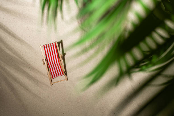 vue aérienne deux chaise de pont, verre de jus, tongs sur le sable à travers les branches du palmier et du palmier d’ombre. voyage, vacances, été, concept romantique. vue supérieure. - beach tropical climate palm tree deck chair photos et images de collection