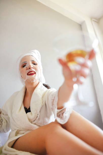 istock Girlfriends with masks on their faces drink champagne while lying in bed. 1252442771