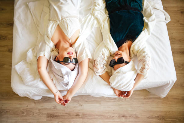 girls in pajamas, bathrobes and sunglasses are lying on the bed. - political party concepts glamour friendship imagens e fotografias de stock