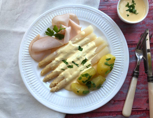 aspargos brancos com molho hollandaise, batatas cozidas e presunto. - hollandaise sauce fotos - fotografias e filmes do acervo