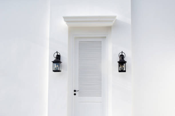 Iron lanterns closed to white door on the wall. Outdoor entrance interior design