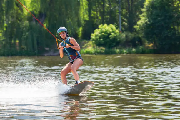 Woman riding wakeboard. Cuts waves and raises splash in a summer lake