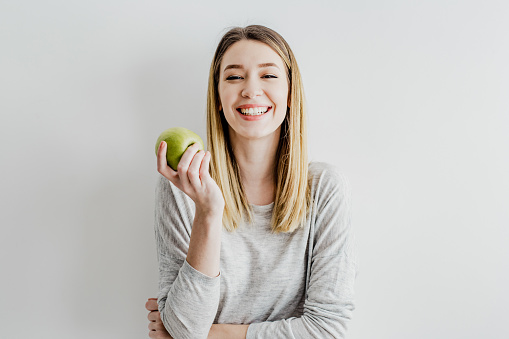 Studio shot of a young woman holding an apple