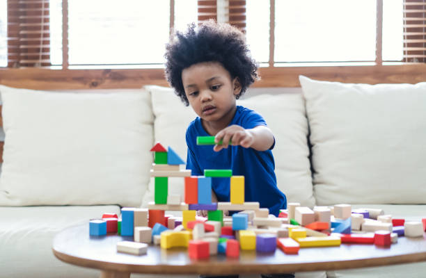feliz afro-americano menino bonito criança brincar com blocos de madeira construção sobre a mesa em casa. aprendendo conceito criativo - block child play toy - fotografias e filmes do acervo