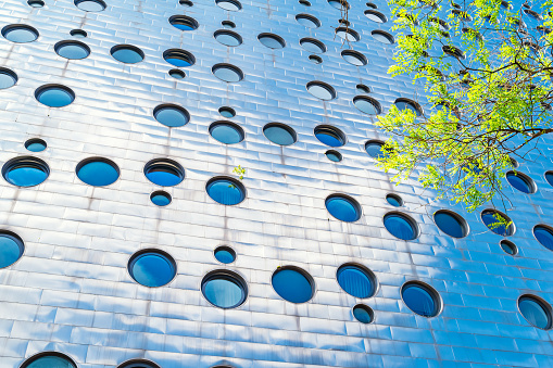 The modern facade of the Dream Downtown Hotel with porthole windows and steel cladding in the Chelsea district of Manhattan, New York City, USA on a sunny day.