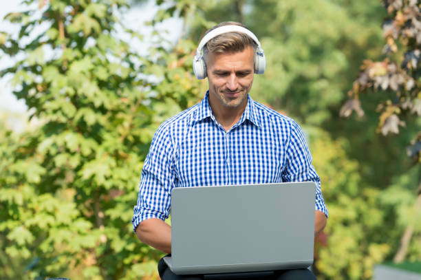 istock Just me and my computer. Handsome man use computer outdoor. Computer for business and gaming. Portable personal computer. Laptop headphones. New technology. Modern life. Mobile lifestyle 1252459137