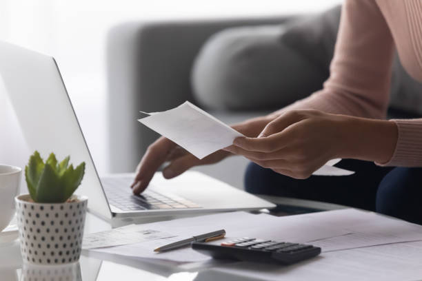 istock Close up woman holding receipt, using laptop, calculating bills 1252459204