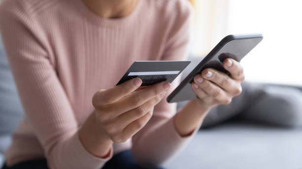 cierre las manos femeninas sosteniendo tarjeta de crédito y teléfono inteligente - application software telephone social media smart phone fotografías e imágenes de stock