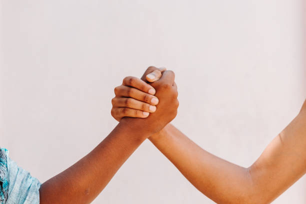 istock Black and white human hands in a modern handshake to show each other friendship and respect - Arm wrestling against racism 1252460310