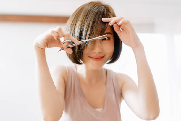 Closeup Portrait Of Happy Young Asian Woman Having Her Hair Cut With  Scissors At Home Shes Stay At Home During The Coronavirus Pandemic Self Hair  Care During Quarantine Stock Photo - Download